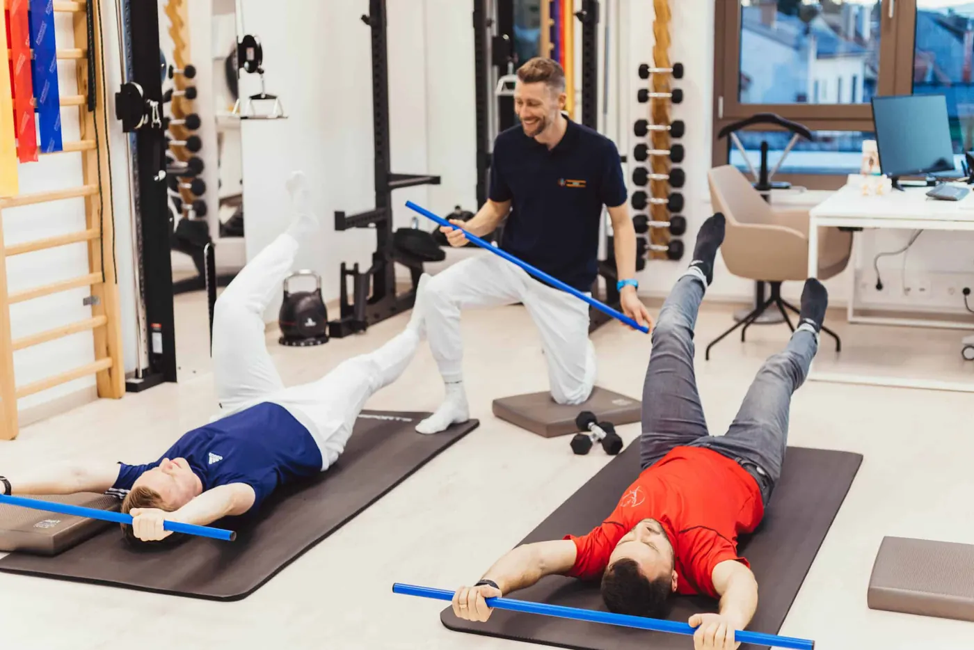 Physiotherapeut begleitet Gruppentraining mit Stäben